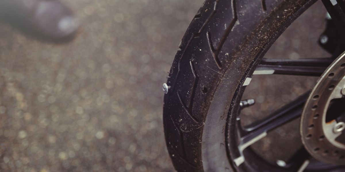 Punctured motorcycle wheel, a nail sticks out of the tire, tire fitting — Photo
